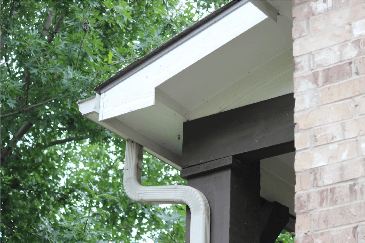 Technician performing hands-on gutter repair on a residential property